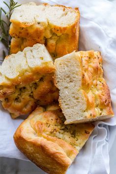 slices of garlic bread sitting on top of a white napkin next to a sprig of rosemary