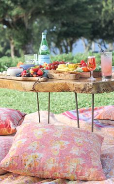 a picnic table with fruit and drinks on it in the middle of a grassy area