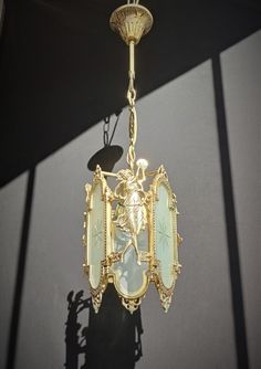 a gold chandelier hanging from the ceiling in front of a black wall with shadows on it