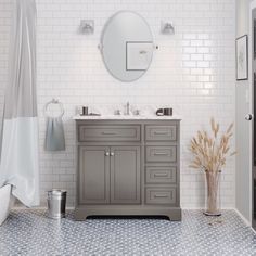 a bathroom with white brick walls and gray vanity, grey cabinetry, and round mirror