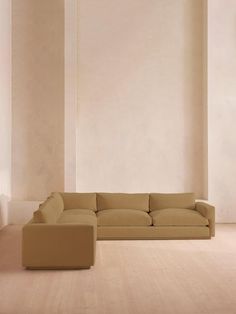 a beige couch sitting in the middle of a living room next to a white wall