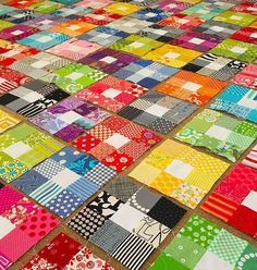 a large patchwork quilt is laying on the floor with many different colors and patterns