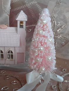 a small pink christmas tree sitting on top of a table next to a doll house