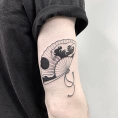 a man with a tattoo on his arm holding a parasol in the shape of a fan