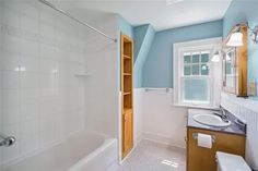 a bathroom with blue walls and white fixtures, including a sink, shower, toilet and bathtub