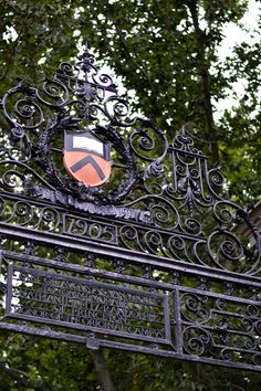 an iron gate with a shield on it and trees in the background