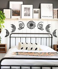 a bed with white sheets and black metal headboard next to pictures on the wall