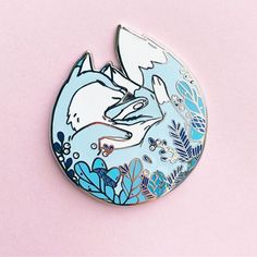 a blue and white brooch with an image of a cat on it's back