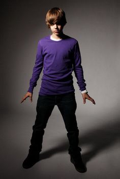 a young man in a purple shirt is posing for a photo with his hands out