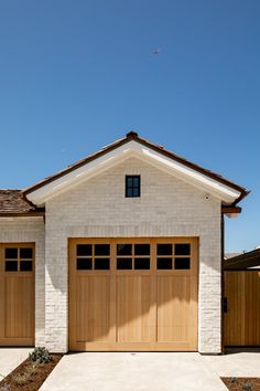 a white brick house with two brown garage doors