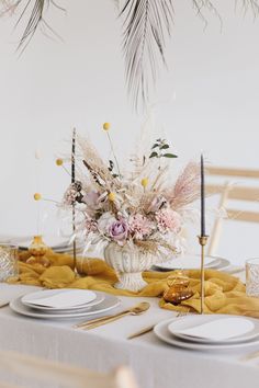 the table is set with plates, silverware and flowers in a vase on it