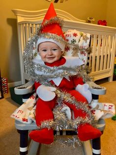 a baby in a santa clause outfit sitting on top of a christmas tree