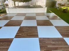 a large checkered dance floor in the middle of a yard with white and brown tiles on it