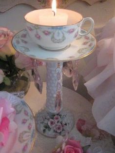 a teacup and saucer with a lit candle in it sitting on a table