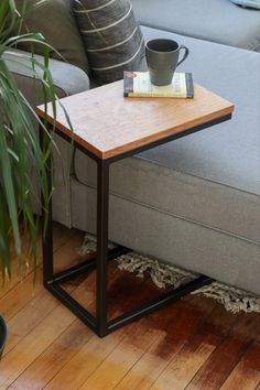 a coffee table sitting on top of a gray couch next to a plant and a book