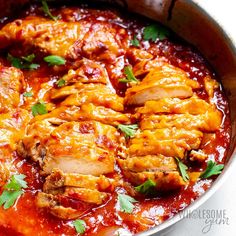 a pan filled with meat covered in sauce and garnished with parsley