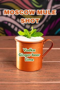 a moscow mule shot mug sitting on top of a wooden table with the words vodka ginger beer line