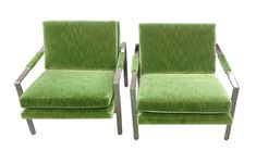 a pair of green velvet chairs with chrome frame arms and foot rests on white background