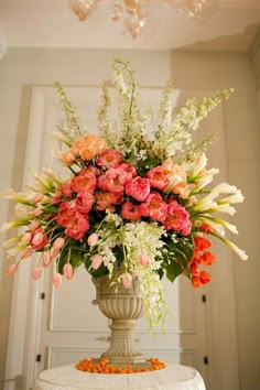 a vase filled with lots of flowers sitting on top of a table next to a chandelier