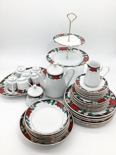 a table topped with lots of white plates and cups covered in red flowers on them