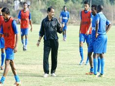 a man standing on top of a soccer field next to other men in blue and red uniforms