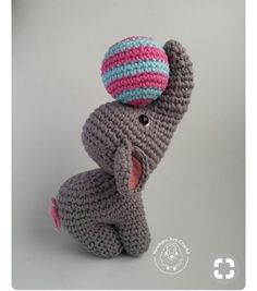 a crocheted elephant with a pink and blue ball on it's head