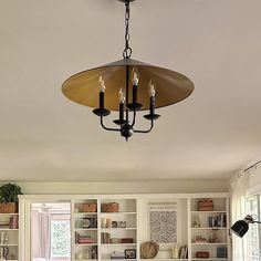 a chandelier hanging from the ceiling in a living room with built - in bookshelves