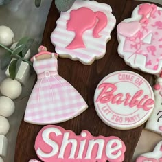 decorated cookies with pink and white designs are on a wooden table next to other decorations