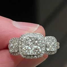 a close up of a person's hand holding a ring with three diamonds on it