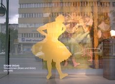 there is a window display with a woman in a yellow dress and man in the background