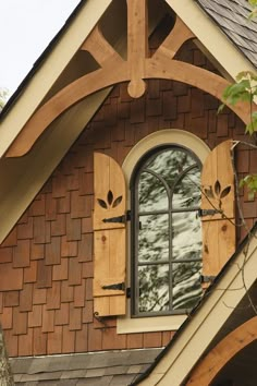 an arched window with wooden shutters on the side of a house's roof