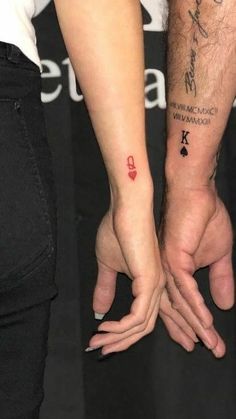 two people are holding hands with tattoos on their arms and the other hand has a red heart