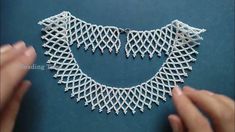 a woman is working on a necklace made with white thread and beadwork,