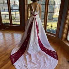 a woman standing in front of a window wearing a dress with red and white trim