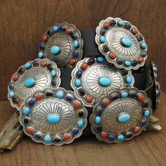 Vintage sterling silver multi-stone oval-shaped stamped concho belt.  There is no artist hallmark on this piece.  This concho belt features turquoise, onyx, coral, and lapis in the stone design.  Each concho has a center turquoise stone.  Each center stone measures approximately 14.5 mm by 11.5 mm.  There are 11 conchos plus 1 buckle.  The concho's measures 2 15/16" long by 2 1/2" wide.  Each concho has two copper pieces making the concho's adjustable.  brown belt measures 1 3/16" wide.  The len Luxury Sterling Silver Concho Jewelry, Turquoise Men, Concho Belt, Sterling Silver Cuff Bracelet, Tucson Az, Brown Belt, Stone Design, Vintage Turquoise, Sterling Silver Cuff