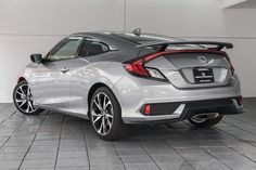 the rear end of a silver honda civic hatchback parked in a white walled room