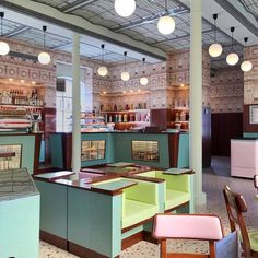 the interior of a restaurant with tables and chairs, lights hanging from the ceiling above