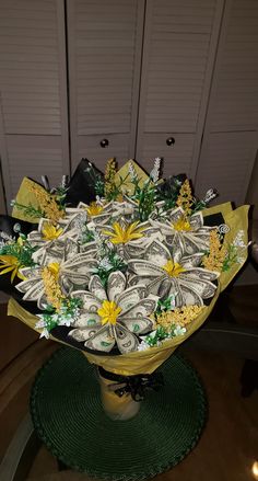 a vase filled with money and flowers on top of a green place mat in front of two white doors