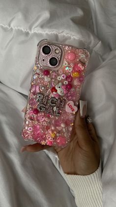 someone is holding their cell phone covered in pink and white buttons with the words hello kitty on it