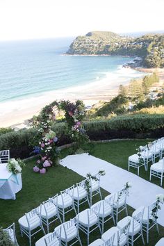 an outdoor wedding setup with white chairs and flowers on the lawn overlooking the ocean in sydney, australia