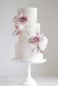 a three tiered wedding cake with pink flowers on the top and white icing