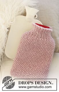 a pink knitted hot water bottle cover sitting on top of a white couch next to pillows