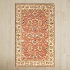 an orange and beige area rug on a wooden floor with white walls in the background