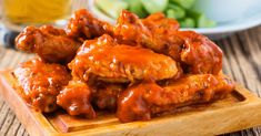 some food is sitting on a wooden board next to a bowl of salad and a glass of water