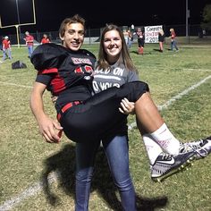 a man and woman posing for a photo on a football field