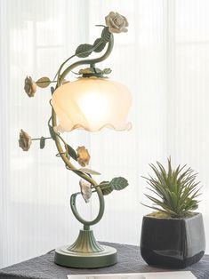 a lamp that is on top of a table next to a potted plant and a book