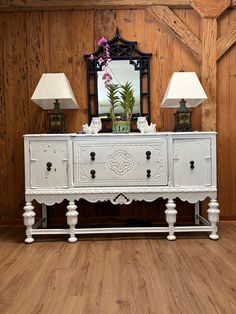 a white dresser with two lamps and a mirror