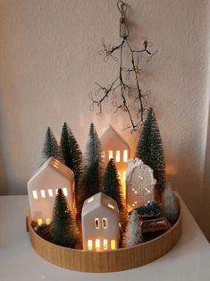 a wooden tray with christmas trees and lit houses in the shape of snow globes