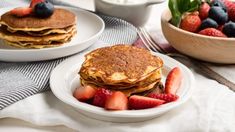 two plates with pancakes and strawberries on them