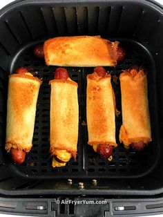 four hot dogs are being cooked in an air fryer